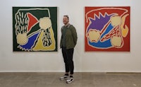 a man standing in front of two colorful paintings